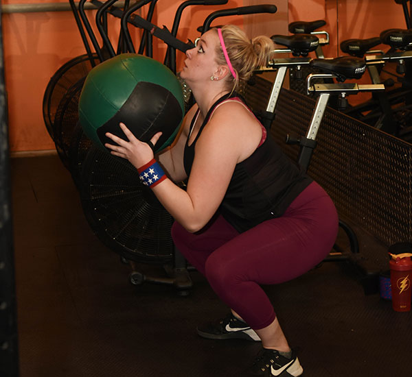 woman crouching with a medicine ball