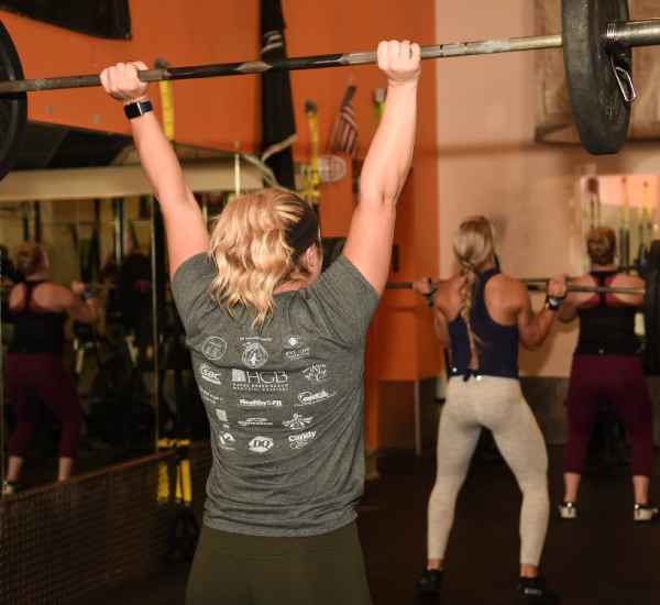 woman holding a weight bar above her head